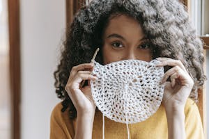 Young woman covering mouth with white crochet napkin